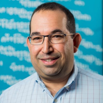 a headshot of Brian LaMacchia against a blue background with white writing on it